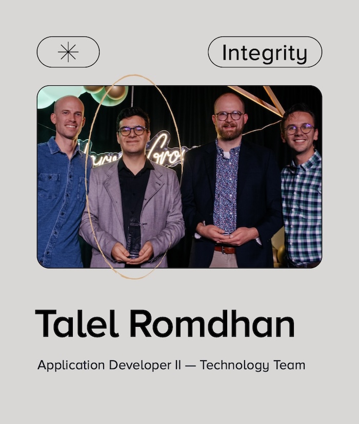 Graphic with text "Integrity" above group photo with 4 men celebrating an award win. Text below reads "Talel Romdhan Application Developer 2, Technology Team"