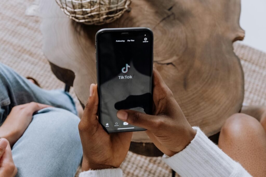 hands holding a mobile phone with TikTok logo on a black screen to represent Harvest Group as a TikTok Shop agency